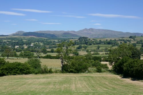 View across fields and trees to a range of mountains in the distance.