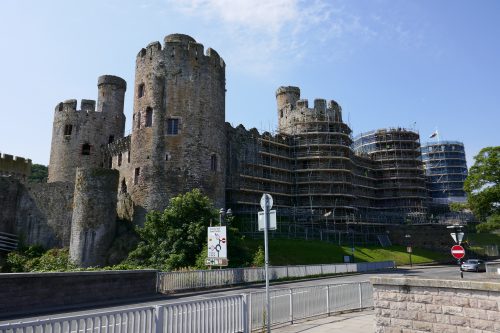 A castle with large round towers. Much of the castle is covered in scaffolding for repair works.